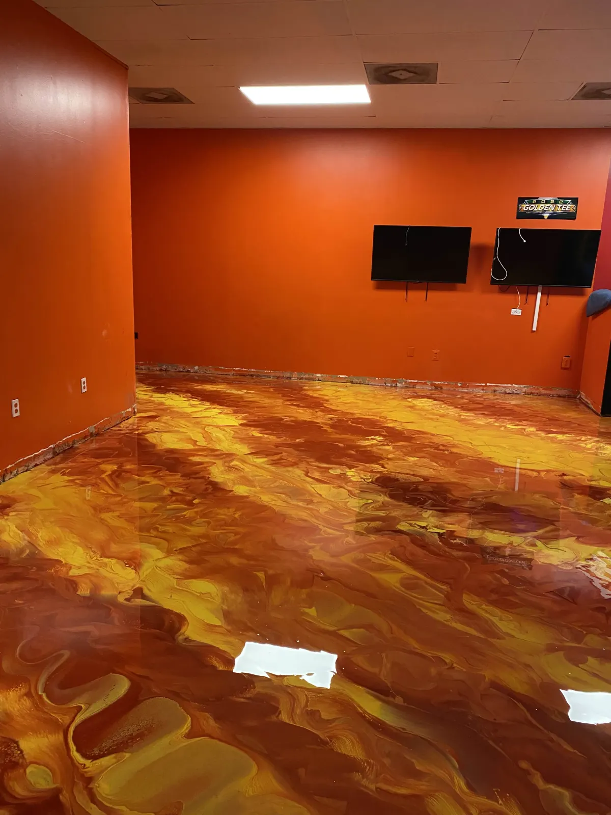 Metallic epoxy flooring installation with orange and gold swirl finish